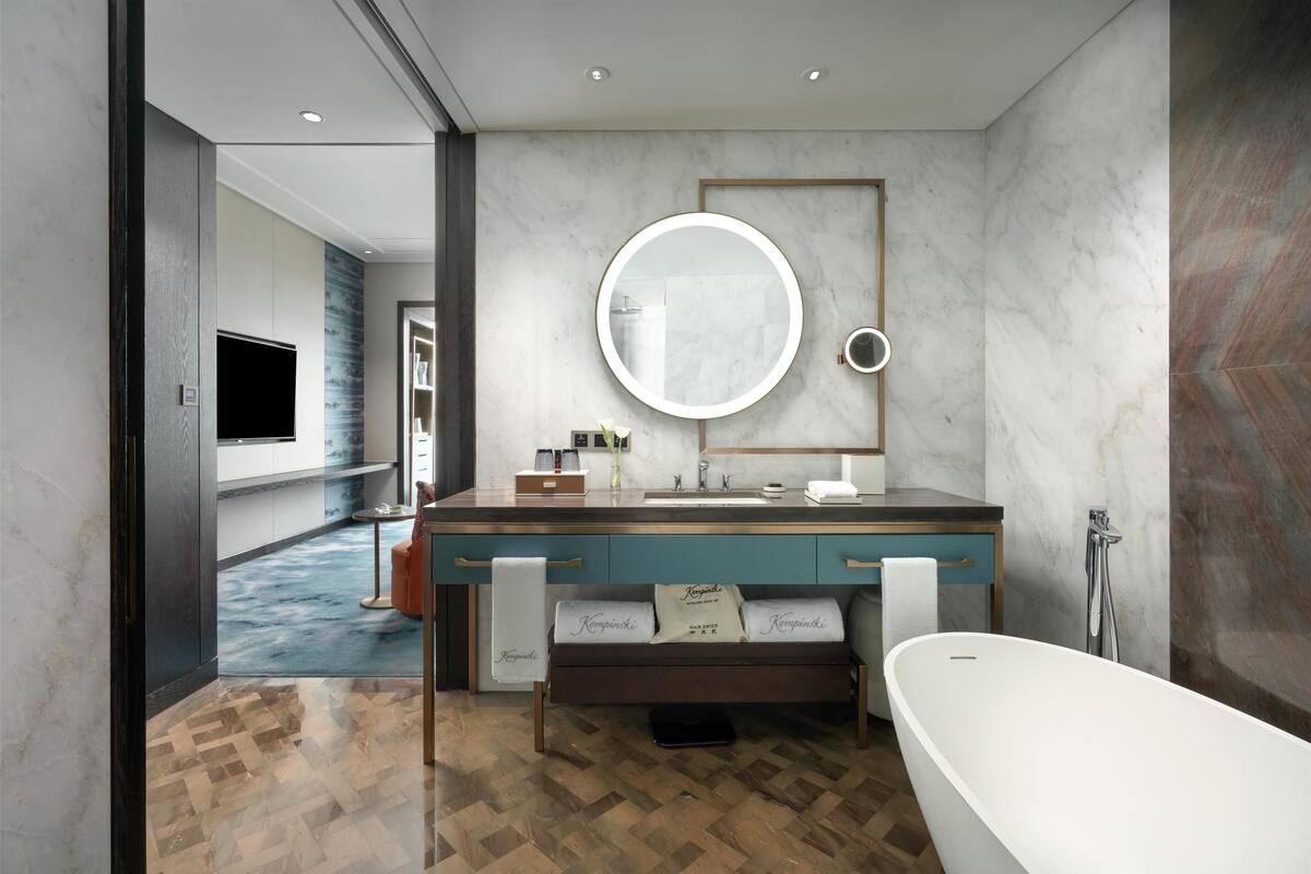 Une salle de bain moderne avec un grand miroir, une baignoire et un meuble-lavabo.