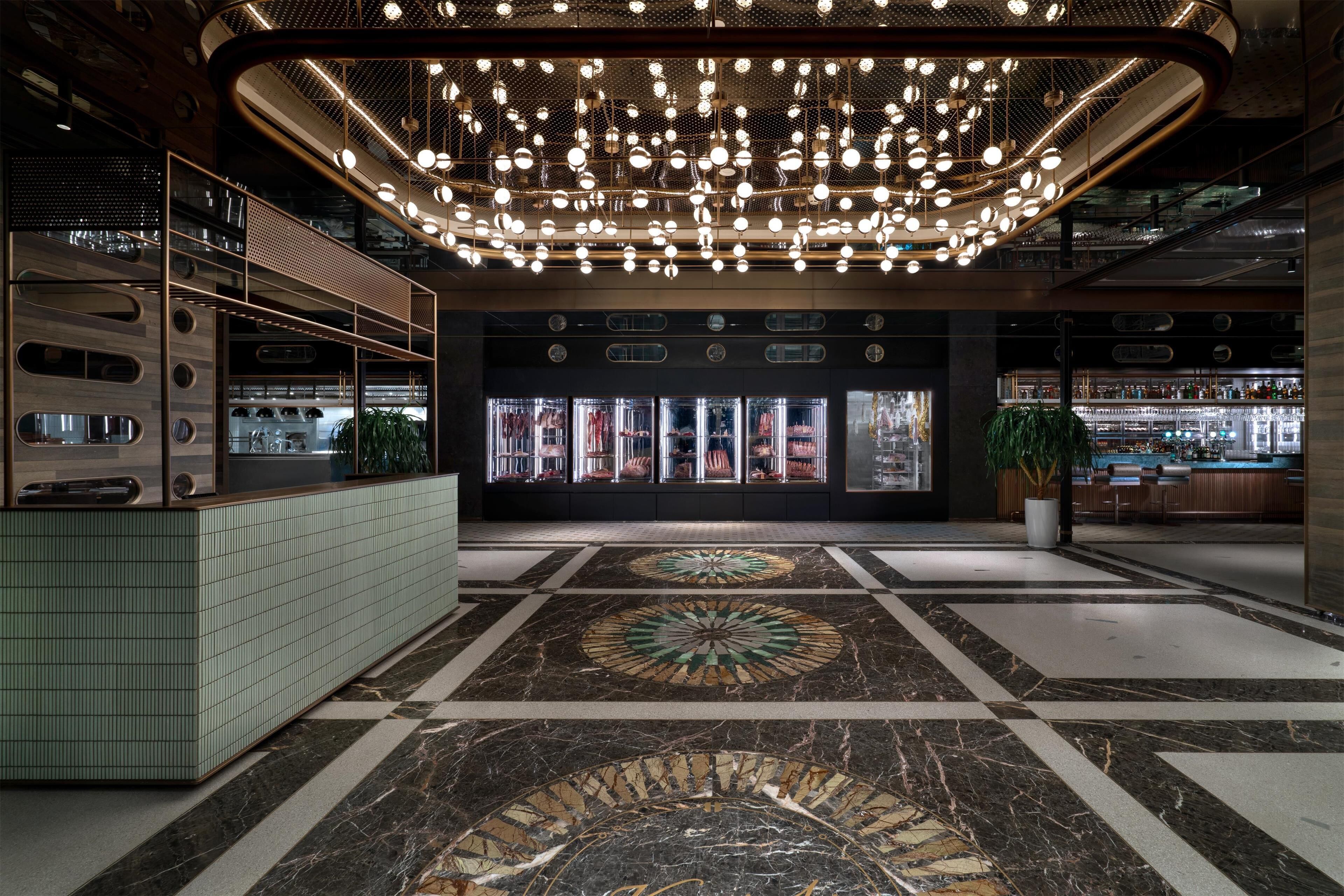 A modern lobby with a central seating area, a bar, and a display of bottled beverages.