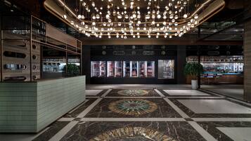 A modern lobby with a central seating area, a bar, and a display of bottled beverages.