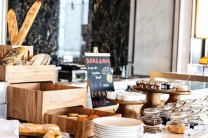 Una mesa de buffet con panes, pasteles y salsas.