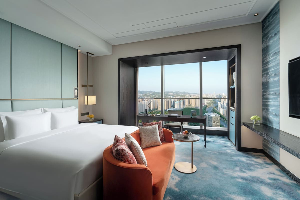 Une chambre d’hôtel avec un grand lit, un canapé, une petite table et un téléviseur.