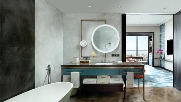 A modern bathroom with a large bathtub, a round mirror, and a vanity with a sink.