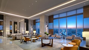 Un hall d’hôtel spacieux au design moderne, comprenant un espace d’accueil, des sièges confortables et de grandes fenêtres offrant une vue sur la ville.