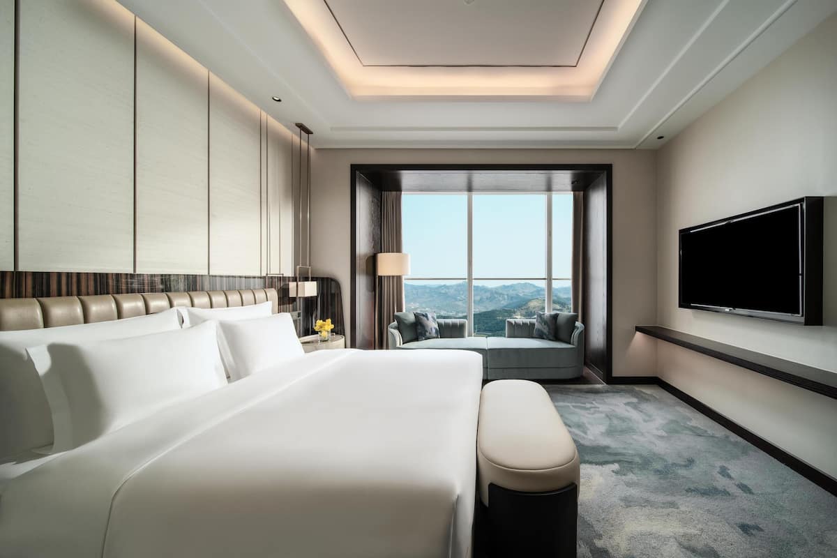 Une chambre d’hôtel dotée d’un grand lit, d’un coin salon, d’une télévision à écran plat et offrant une vue sur l’extérieur.