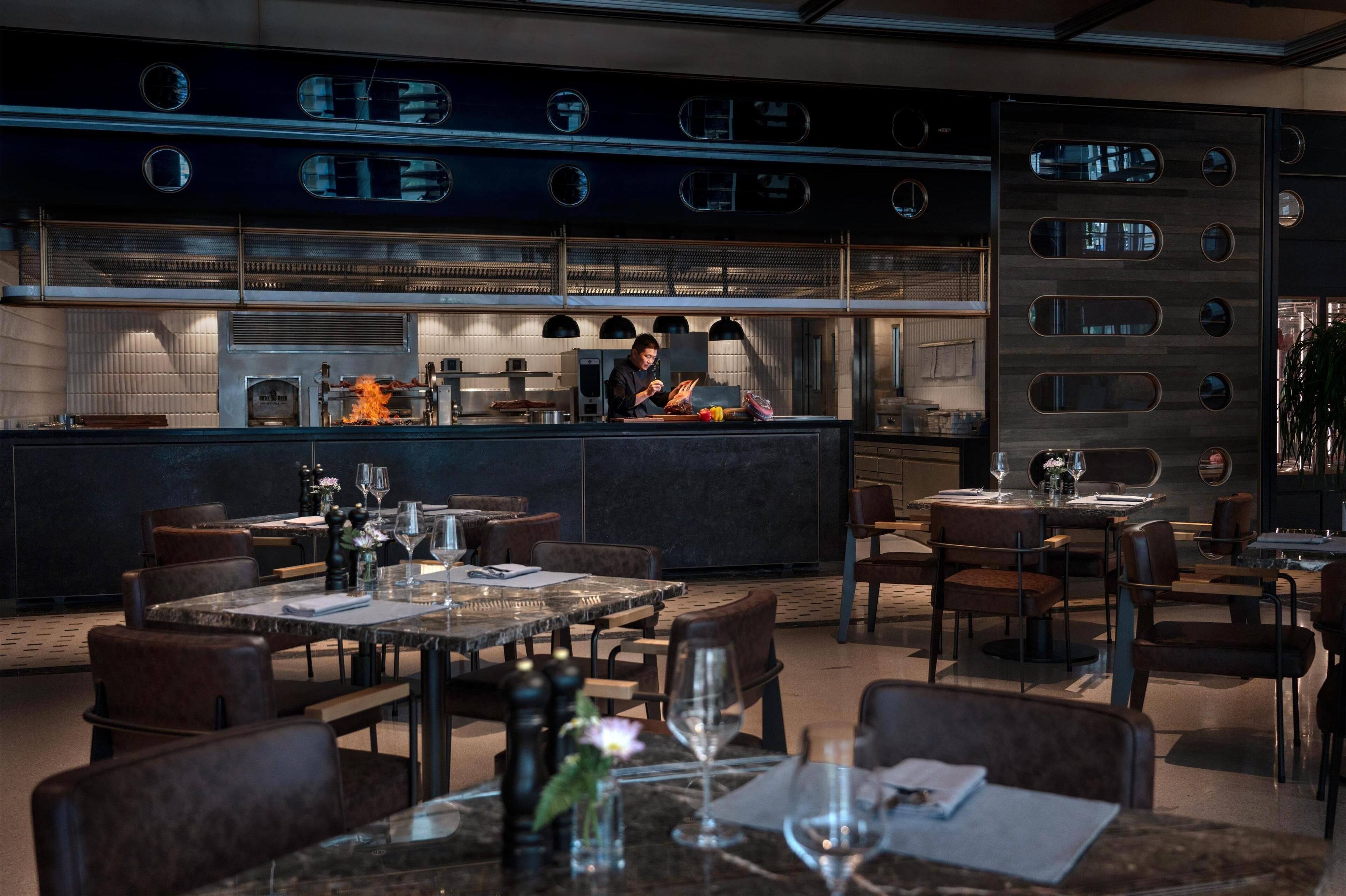 A modern restaurant with a central bar, dining tables, and chairs.