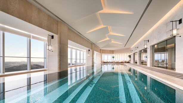 Une piscine intérieure moderne avec des murs en verre transparent, de grandes fenêtres et une vue sur les montagnes.