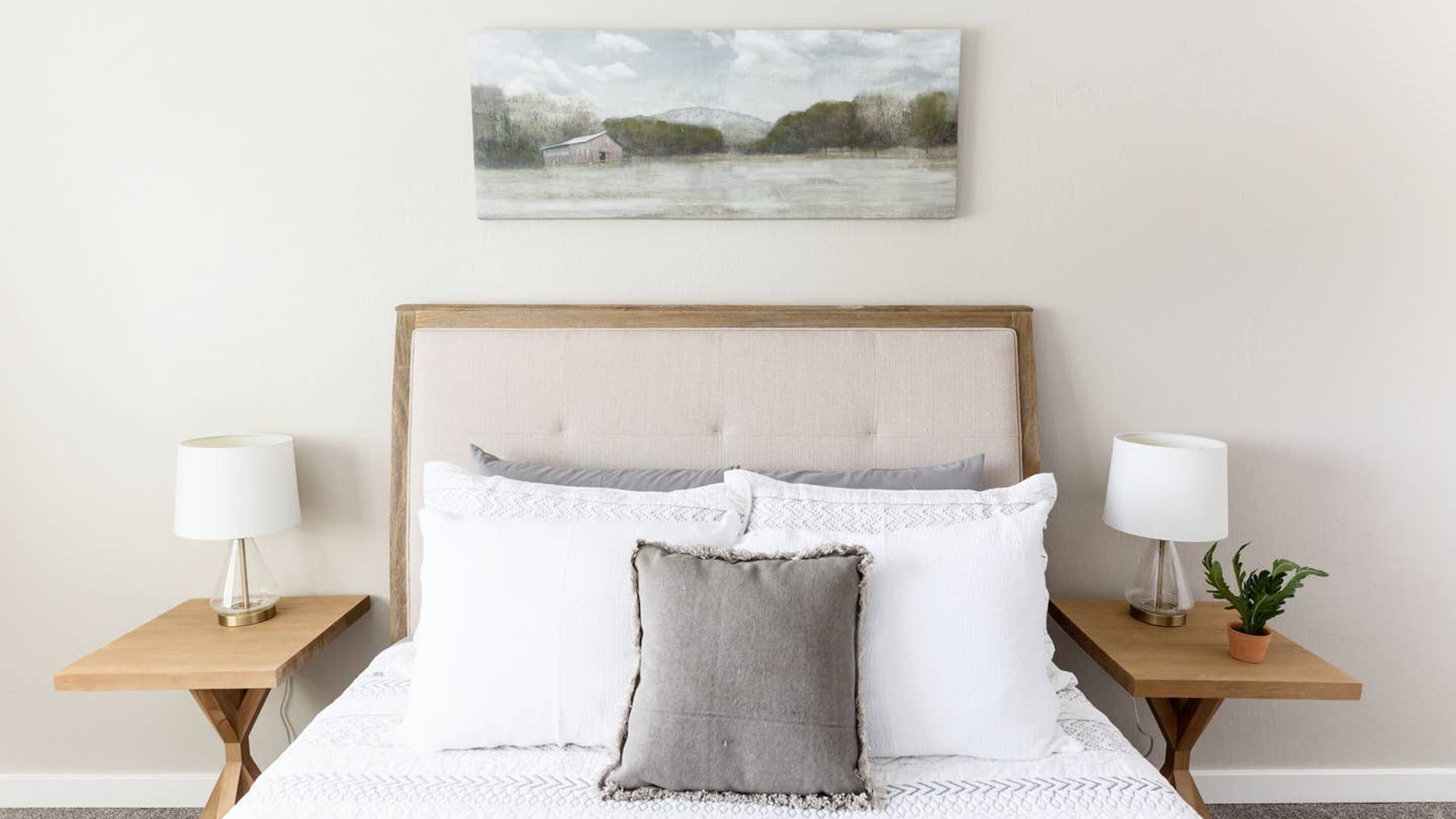 Une chambre avec un grand lit, deux tables de chevet avec des lampes et un tableau au mur.