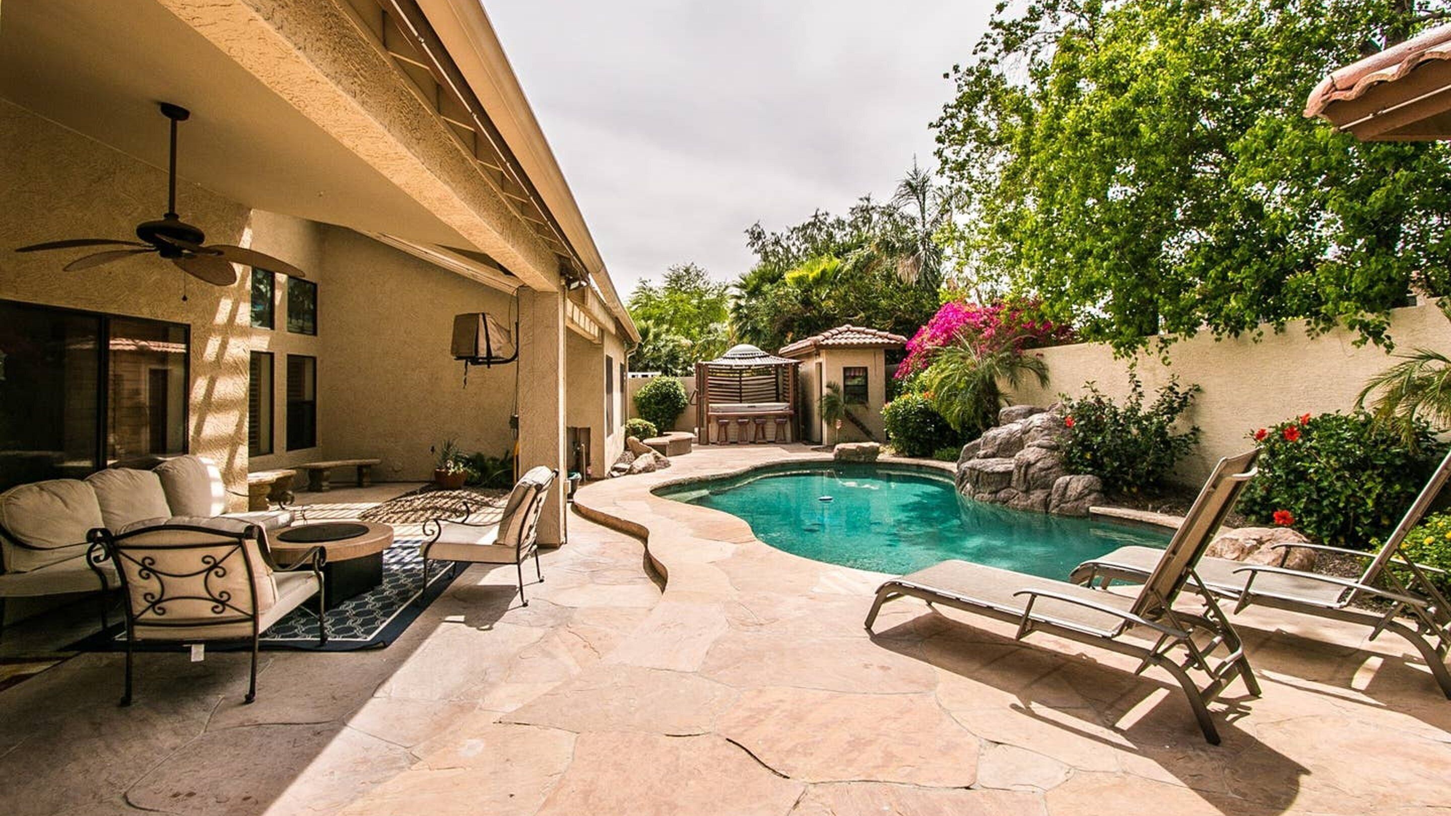 A backyard with a swimming pool, patio furniture, and a pergola.