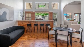 Ein modernes Wohnzimmer mit einer Holztheke, einem schwarzen Sofa und einem runden Tisch mit Stühlen.