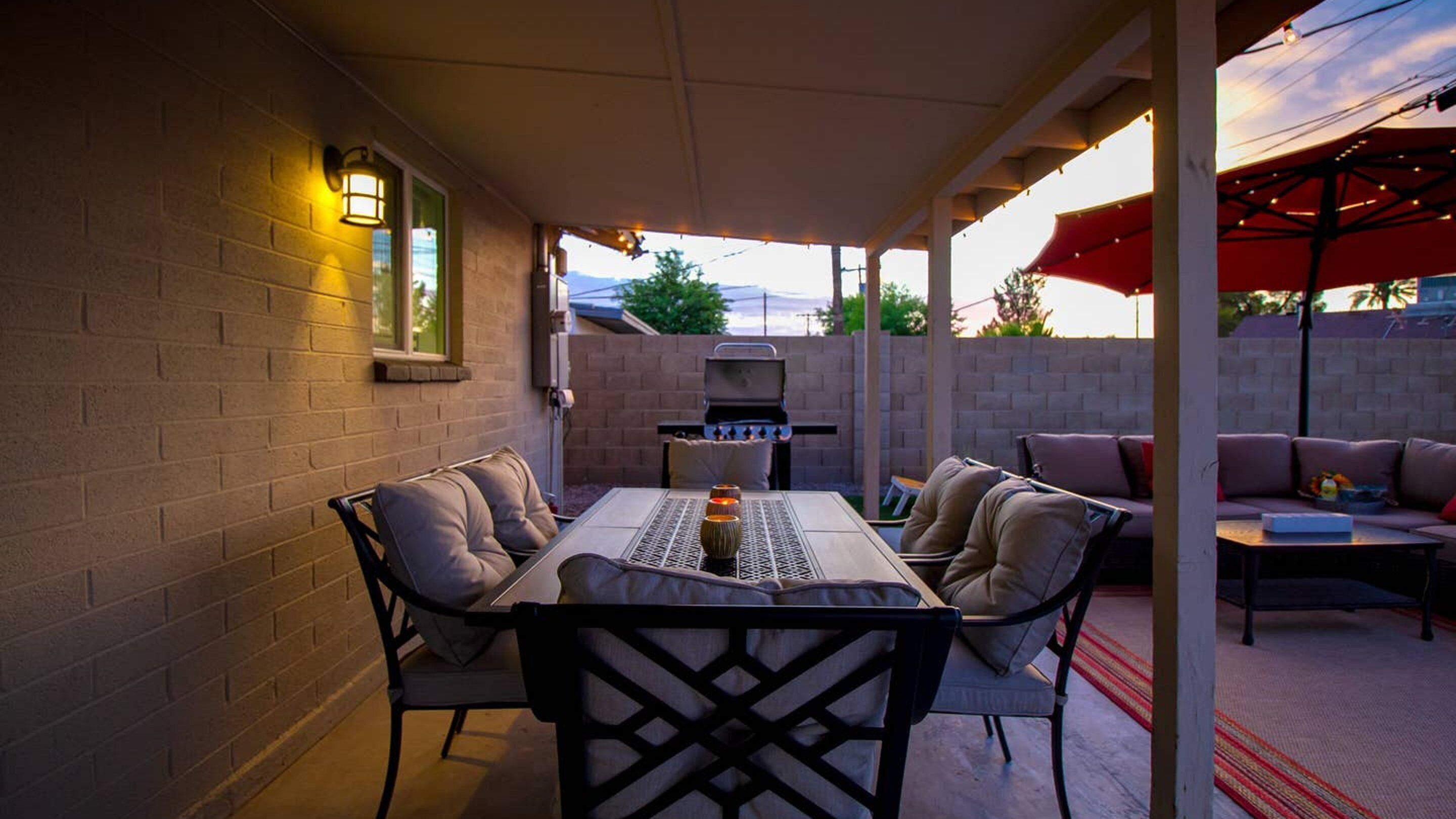 Une terrasse extérieure avec une table et des chaises, un barbecue et un canapé.