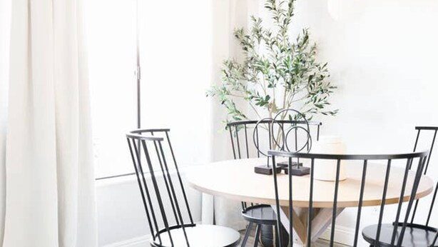 A round dining table with four black chairs, a potted plant, and a candle on the table. - Stylish Old Town 2 Bdrm Ground Floor Condo (Scottsdale)