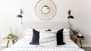 A bedroom with a bed, two bedside tables, a mirror, and wall-mounted lamps. - Stylish Old Town 2 Bdrm Ground Floor Condo (Scottsdale)