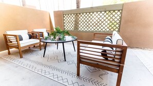 An outdoor patio with wooden furniture, a round table, and a potted plant. - Stylish Old Town 2 Bdrm Ground Floor Condo (Scottsdale)