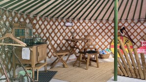 A tent with a green and white striped roof, wooden furniture, and a lattice wall.