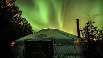 A yurt with a starry night sky and aurora borealis.