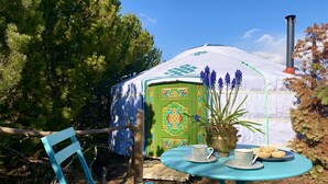 A blue metal chair and table set outdoors with a decorative door and a potted plant with blue flowers.