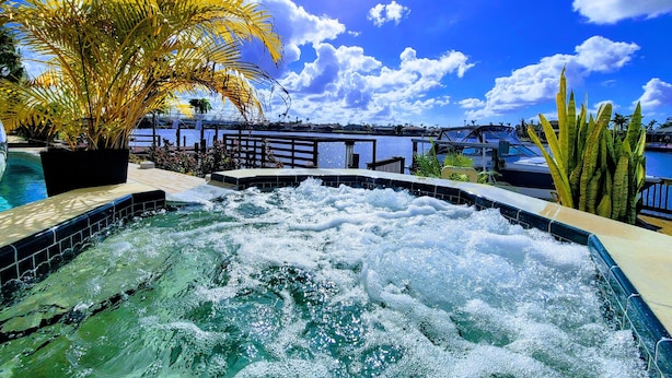 Un bain à remous avec vue sur un port de plaisance et des bateaux, entouré de plantes tropicales.