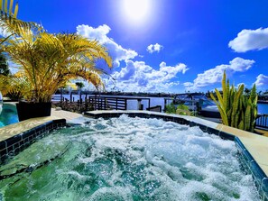 Un jacuzzi con vistas a un puerto deportivo y barcos, rodeado de plantas tropicales.