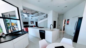 Une cuisine moderne dotée d’un îlot central, de meubles blancs et d’un robinet noir.