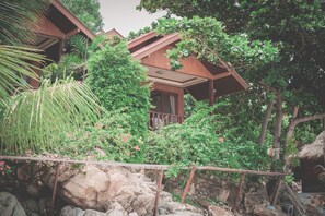 A wooden house surrounded by lush greenery and rocks.