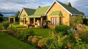 A stone building with a green roof, surrounded by a well-maintained garden with various plants and flowers. - Fouriesburg Country Inn (Fouriesburg)