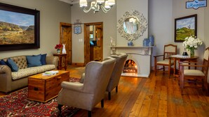 A spacious living room with a fireplace, a chandelier, and a reception sign. - Fouriesburg Country Inn (Fouriesburg)