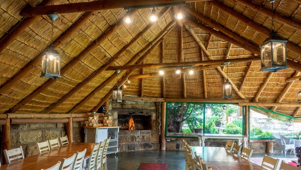 A rustic dining area with a thatched roof, stone walls, and a fireplace. - Fouriesburg Country Inn (Fouriesburg)