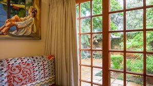 A room with a large window, a painting of a woman, and a patterned cushion. - Fouriesburg Country Inn (Fouriesburg)