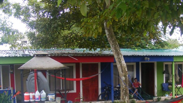 A swimming pool with inflatable rings, a hammock, and a house with a red and blue exterior.