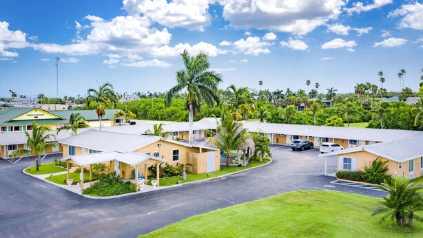 A motel with multiple rooms, a parking lot, and surrounding greenery. - Everglades City Motel - Queen Room, 2 Beds, Kitchenette (Everglades City)