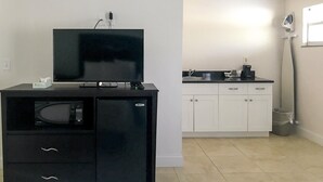 A compact kitchen with a black entertainment unit, a microwave, and a coffee maker. - Everglades City Motel - Queen Room, 2 Beds, Kitchenette (Everglades City)