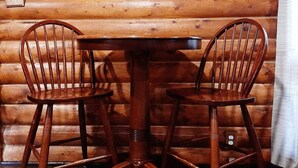 Une table en bois avec deux chaises dans une pièce d’une cabane en rondins.