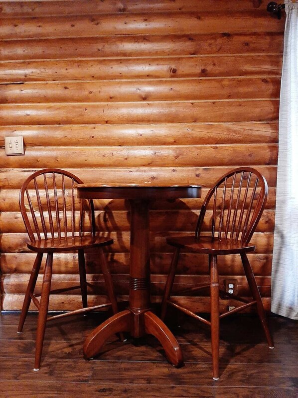 A wooden table with two chairs in a log cabin room.