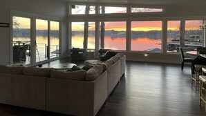 Un salon spacieux avec une grande fenêtre donnant sur un lac, un canapé et un coin repas.