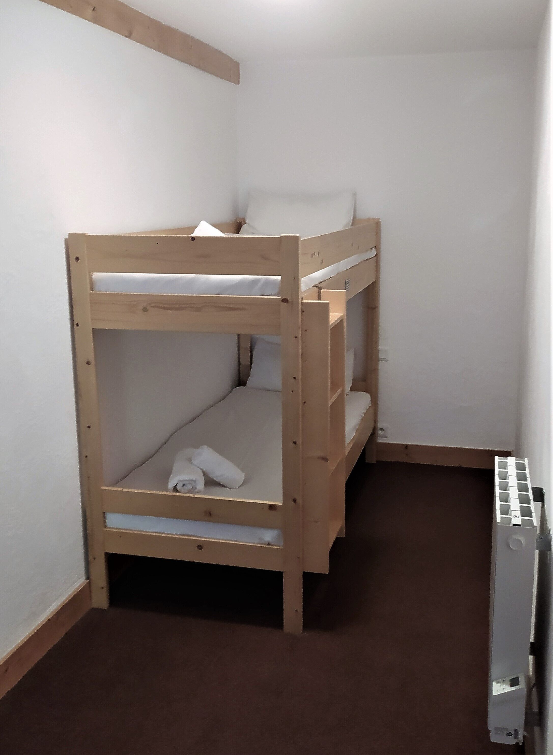 A bunk bed in a room with white walls and a brown carpet.