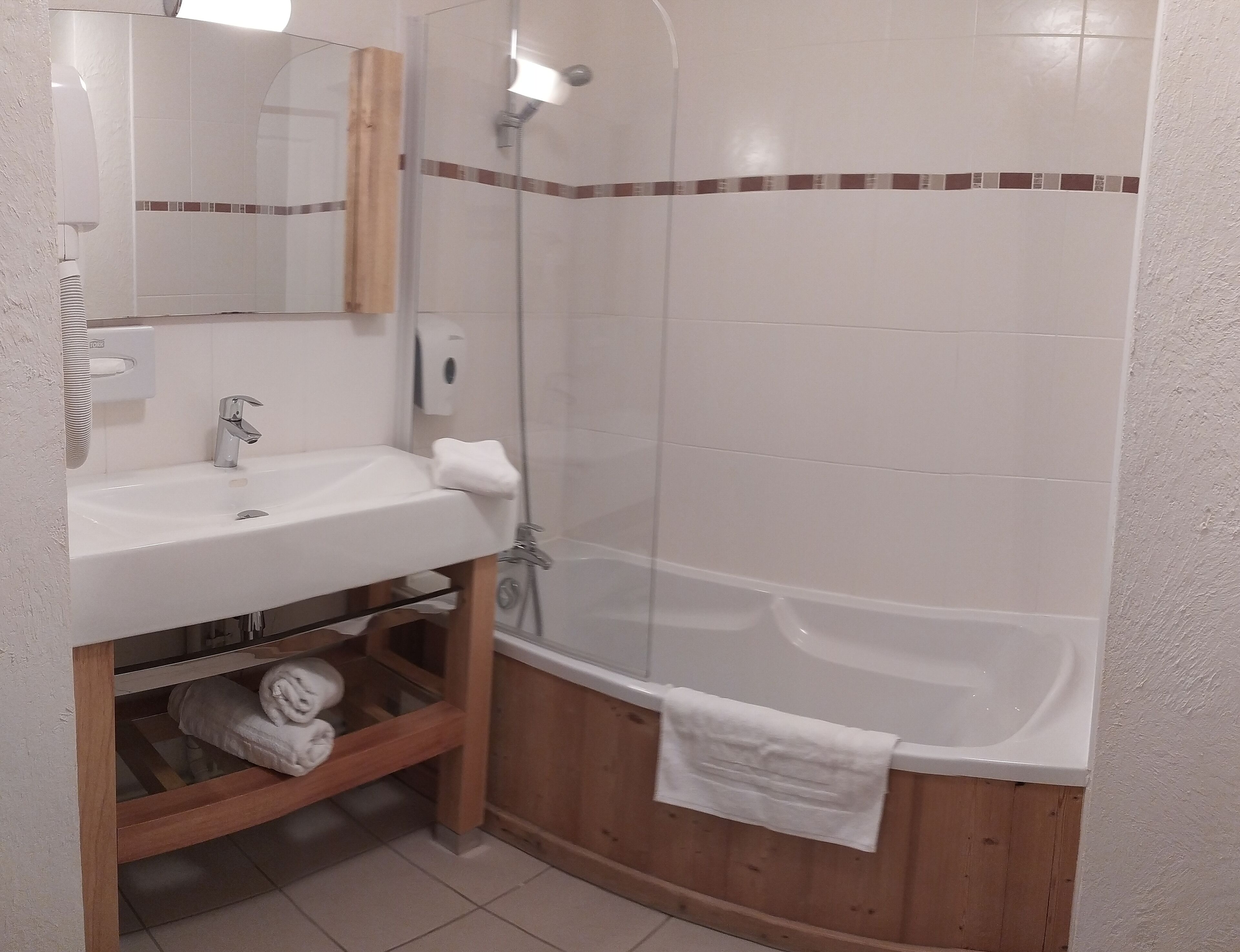 A bathroom with a white sink, a mirror, a wooden cabinet, and a shower enclosure.