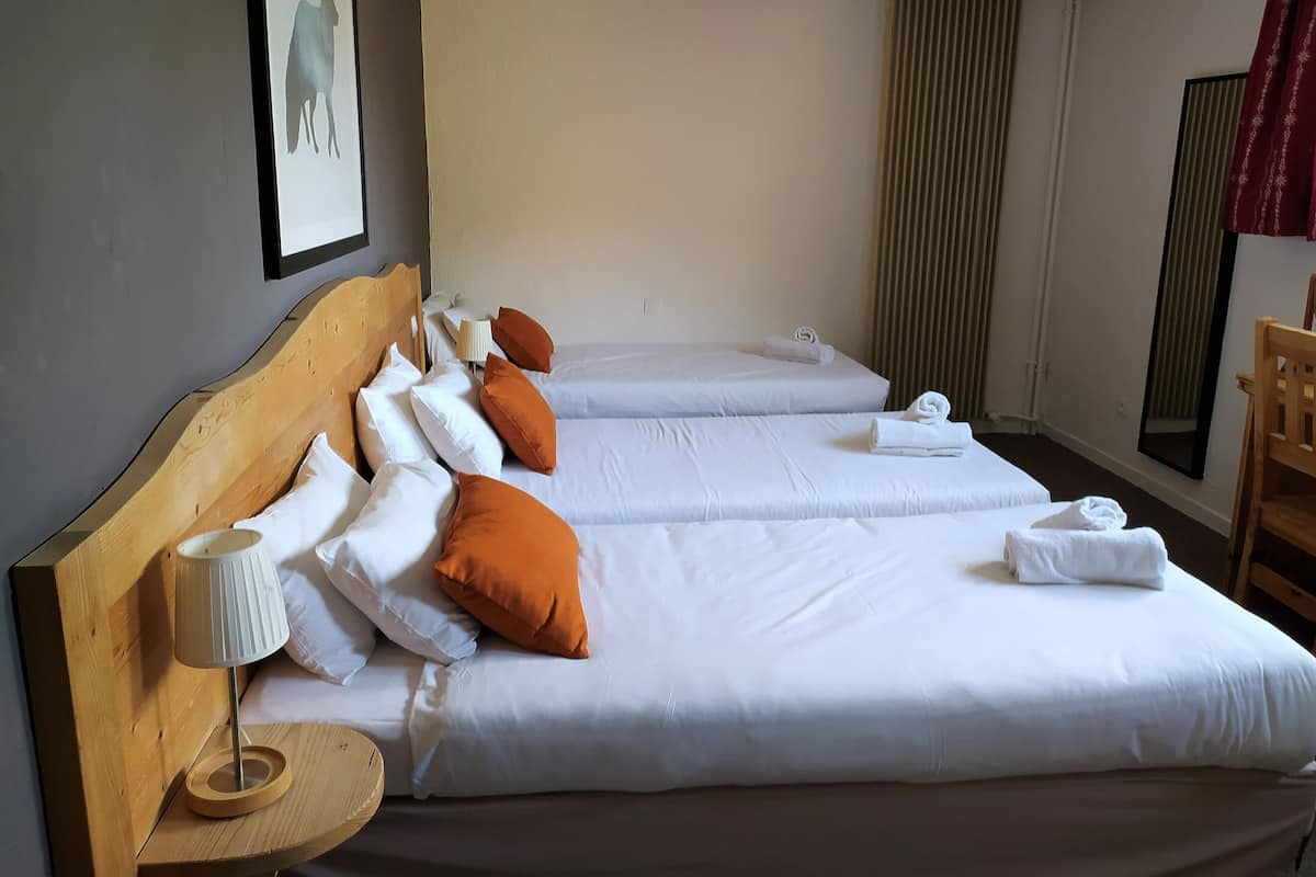 A hotel room with two single beds, a wooden headboard, a bedside lamp, and a mirror.