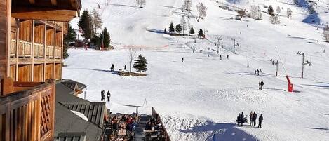 A wooden building with a balcony overlooking a snowy ski slope.