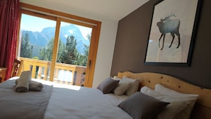 Ein Schlafzimmer mit einem großen Bett, einem Holzkopfende und Blick auf die Berge durch eine Schiebetür.