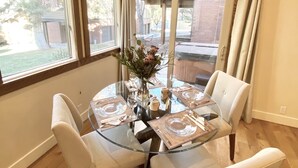 A dining area with a glass table, white chairs, and a vase with flowers. - Prime Skier's Pad for a Magical Vacation (Cottonwood Heights)