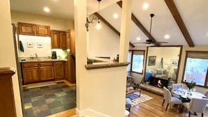 A spacious living area with a fireplace, wooden flooring, and a dining area with white chairs. - Prime Skier's Pad for a Magical Vacation (Cottonwood Heights)
