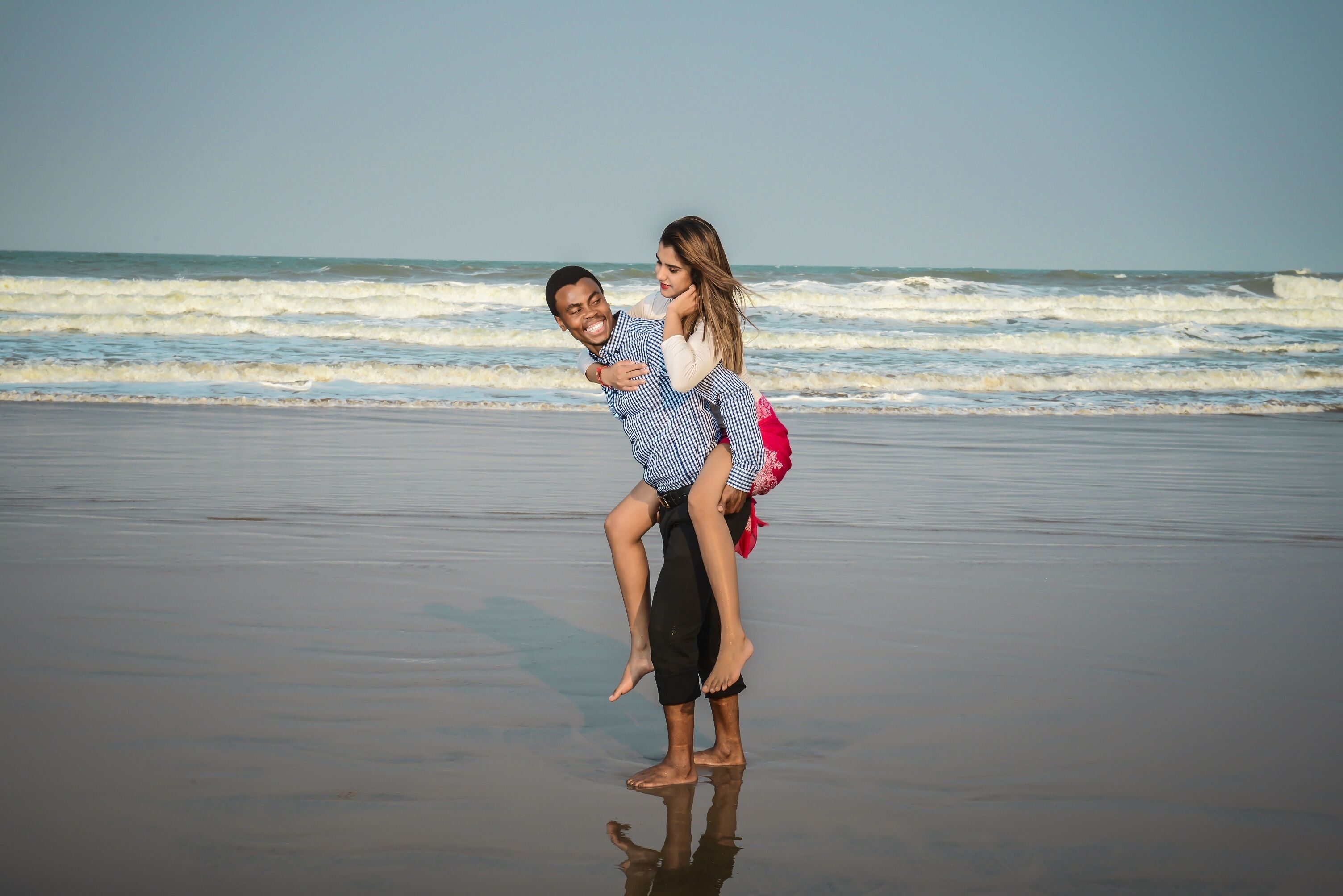 Una pareja en la playa, con olas al fondo.