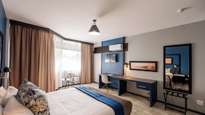 Une chambre d’hôtel avec un lit, un bureau, une chaise et un grand miroir.
