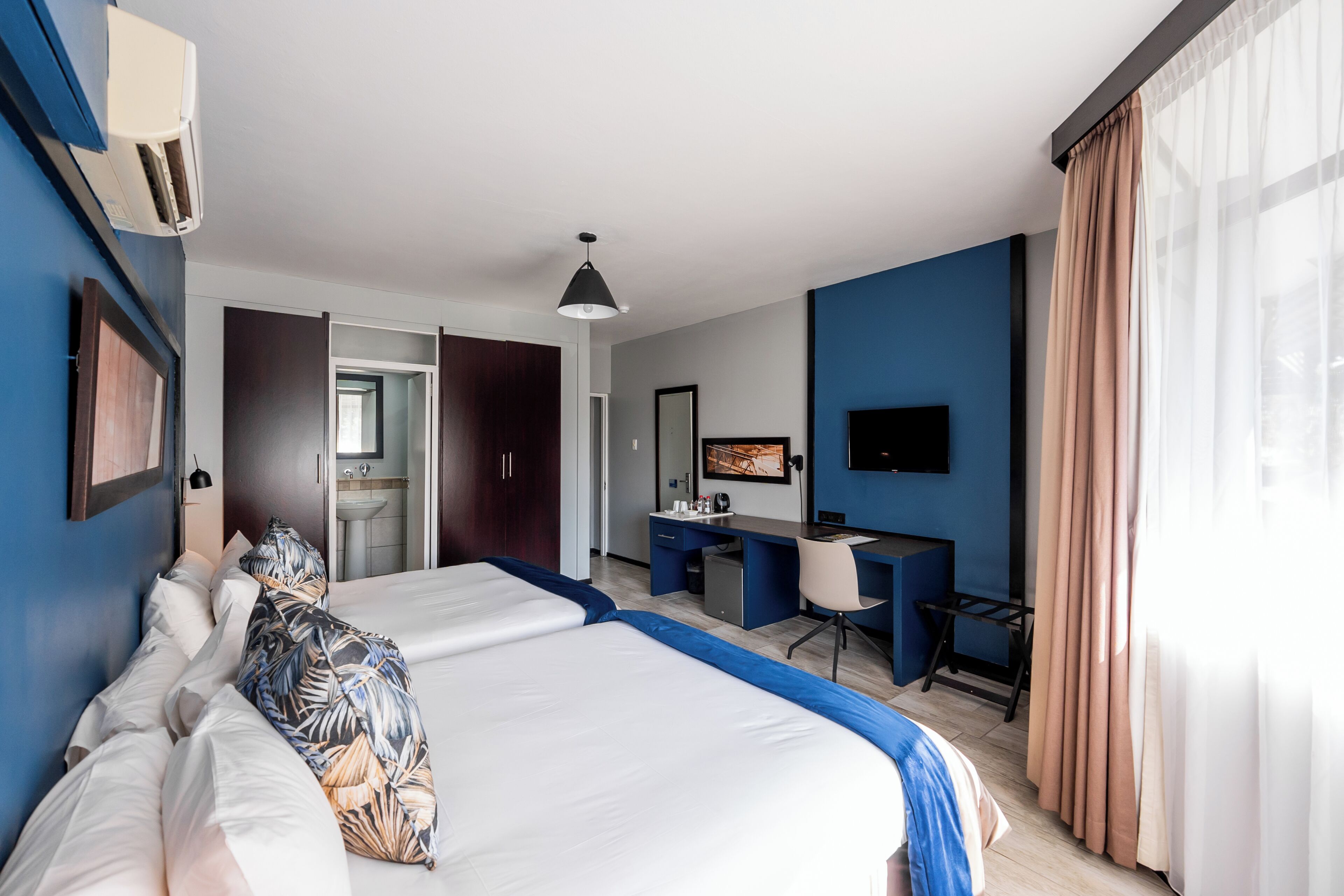 Una habitación de hotel con cama, escritorio y televisión.