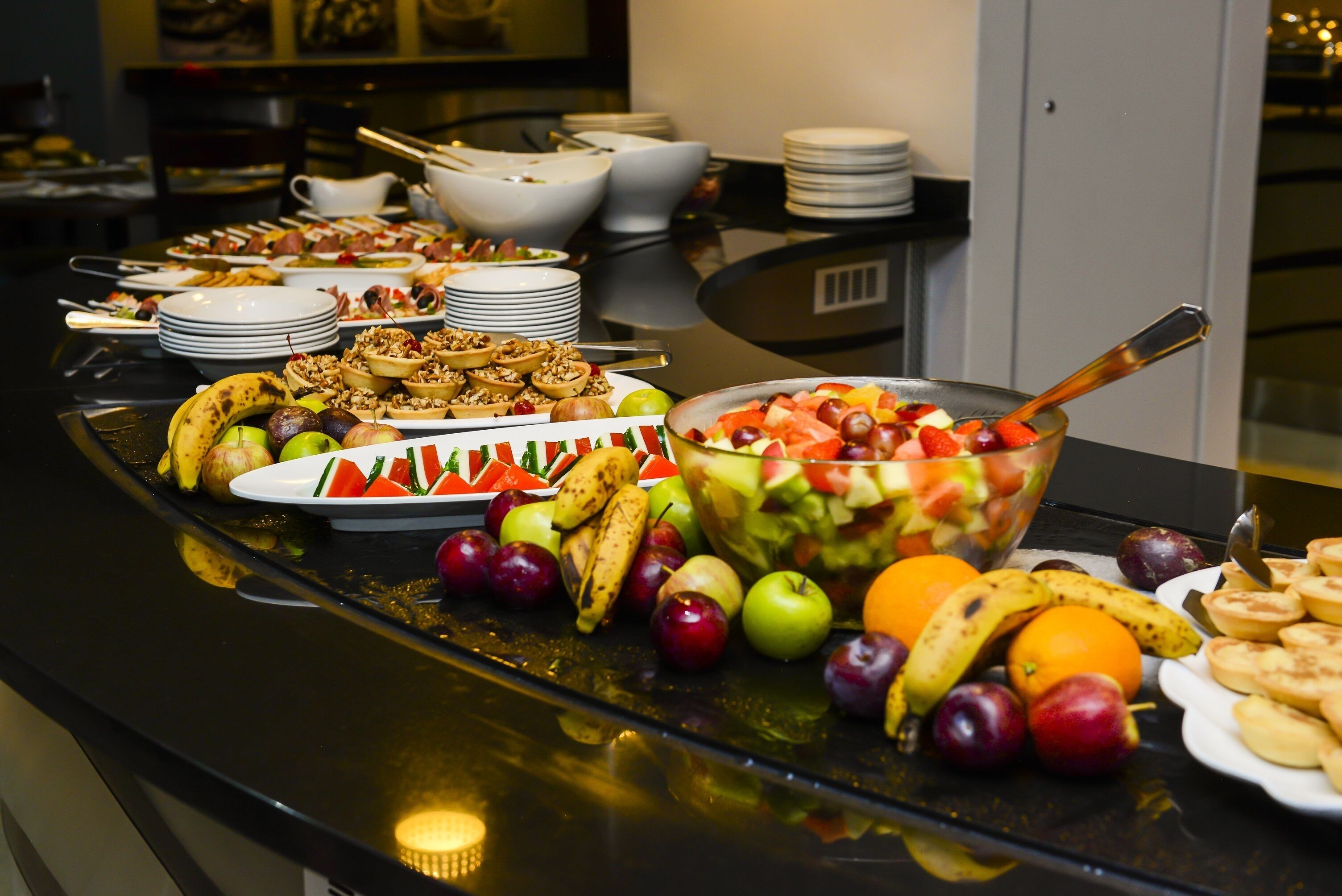 A buffet table with various fruits, vegetables, and dishes.