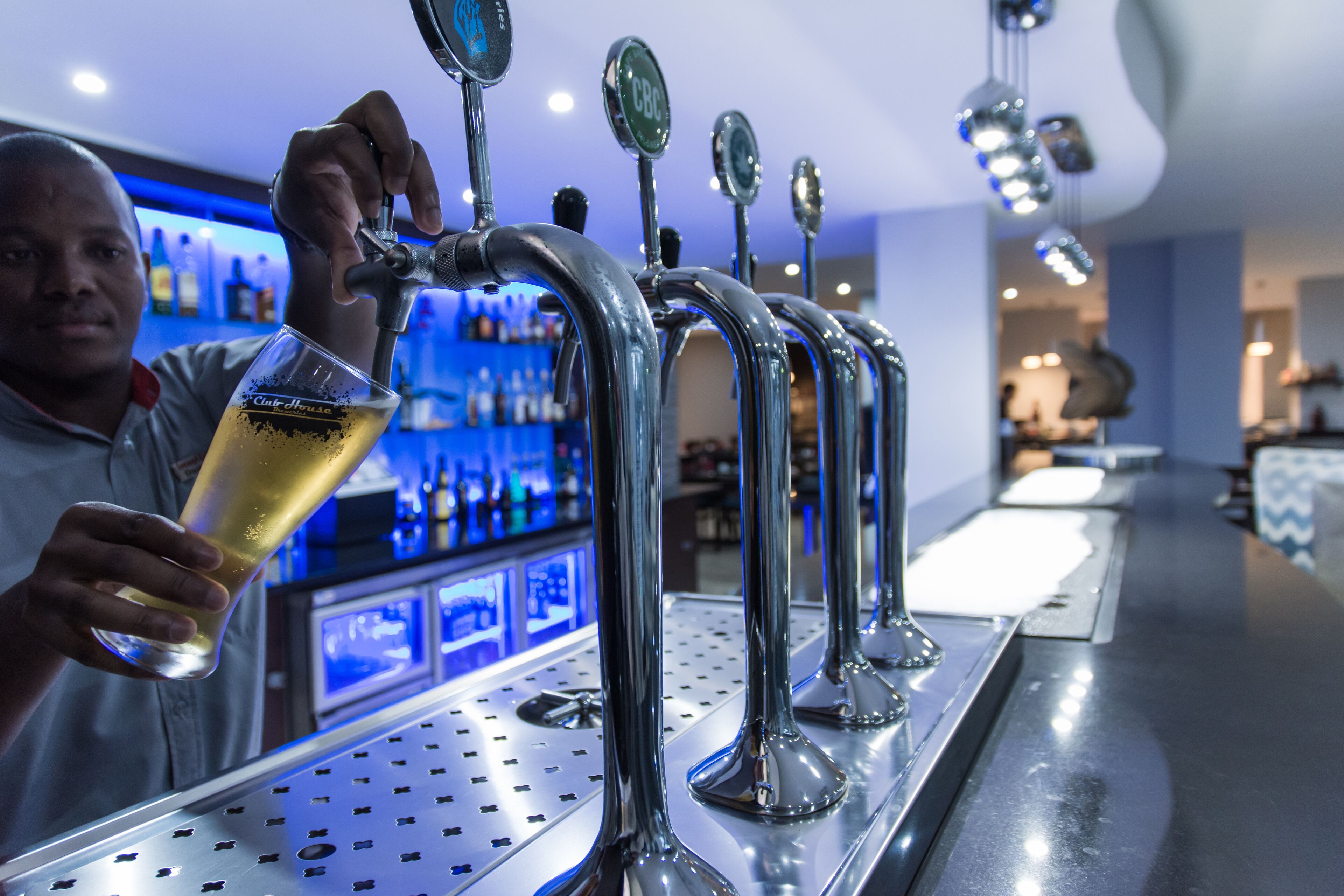 A bar with multiple taps and a person pouring a drink.