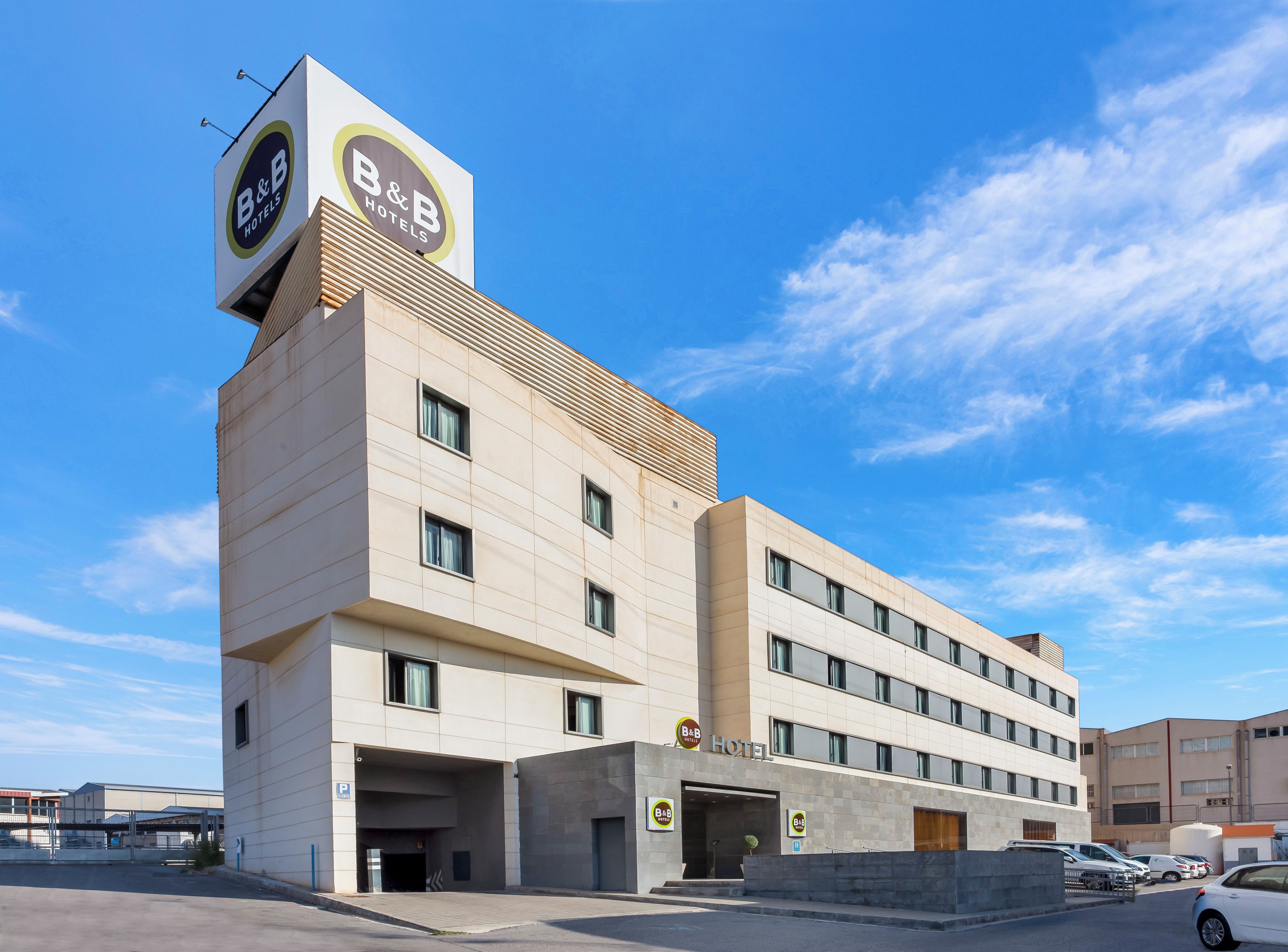 Ein Bed and Breakfast Hotel mit modernem Design, mit einer gut sichtbaren Beschilderung, mehreren Fenstern und einem Parkplatz.
