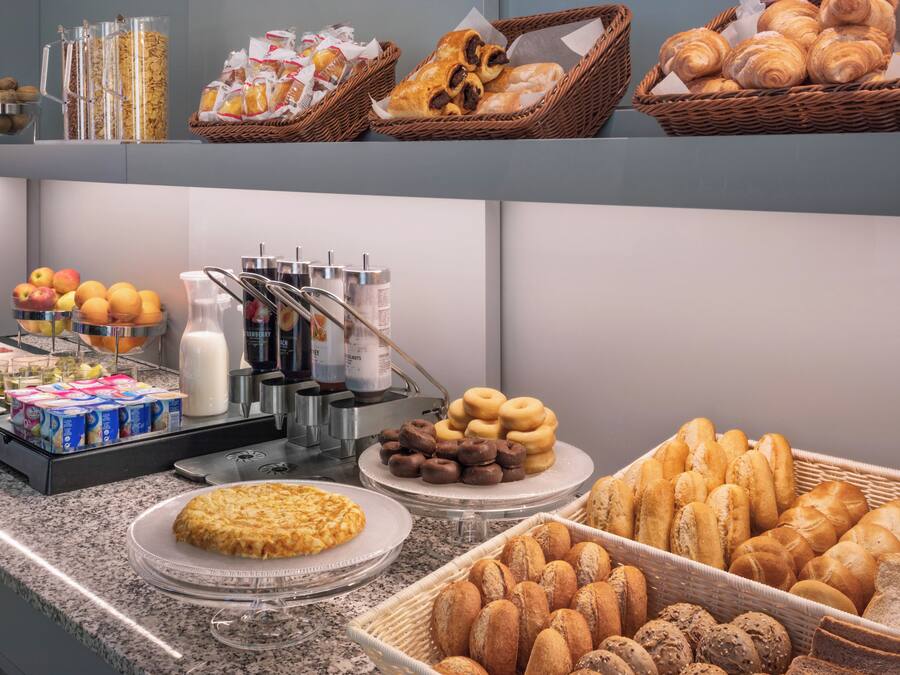 Un bufé con diversas opciones de comida, incluyendo pasteles, frutas y bebidas.