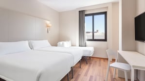 A hotel room with two beds, a desk, a chair, a TV, and a window with a view.