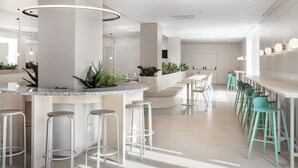 Un área de bar moderna con una barra curva, taburetes blancos y taburetes verdes.